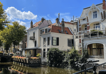 White houses next to a canal. The sky is blue with a few clouds. 